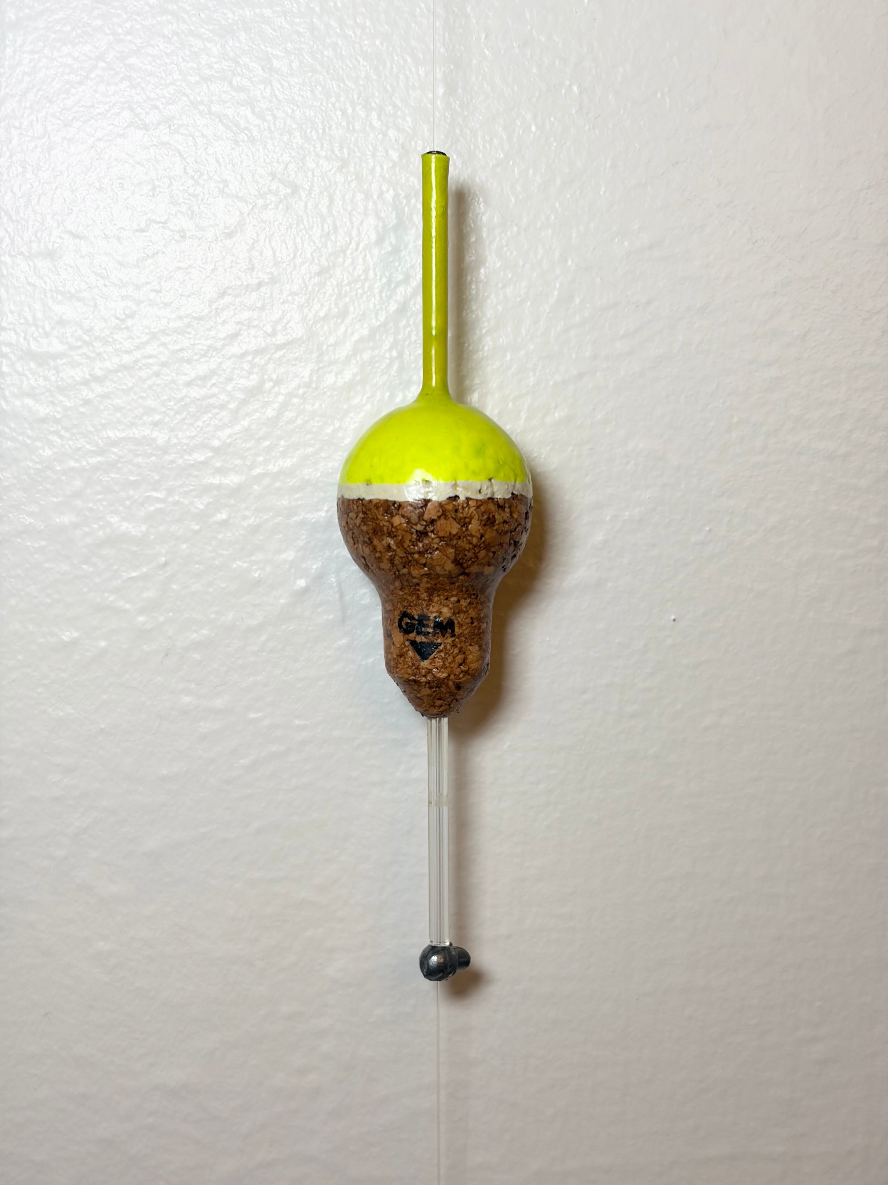 Chartreuse Cork fishing slip float attached to a fishing line, on a white background.