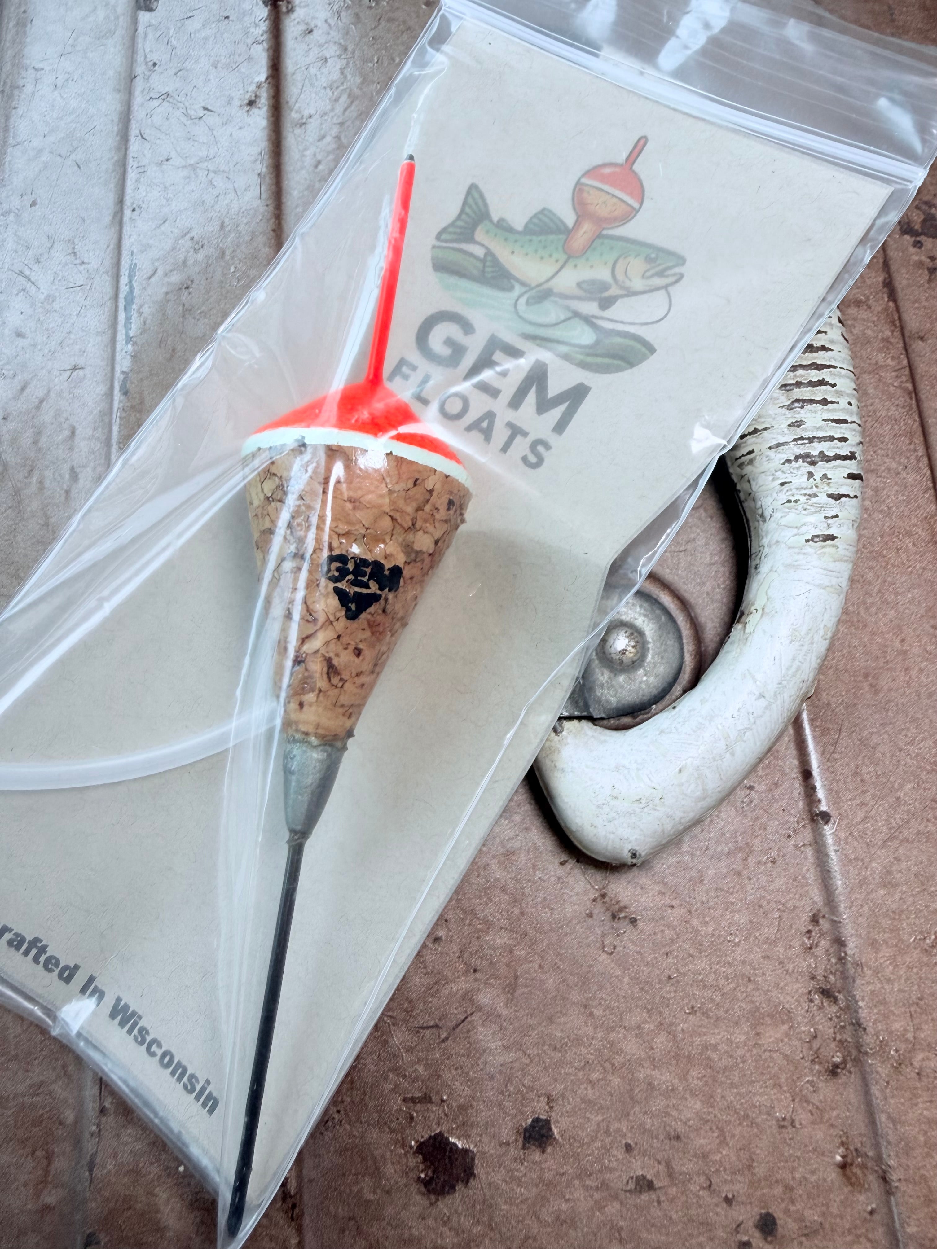 Orange weighted fixed cork fishing float, inside plastic bag on an antique tackle box. 