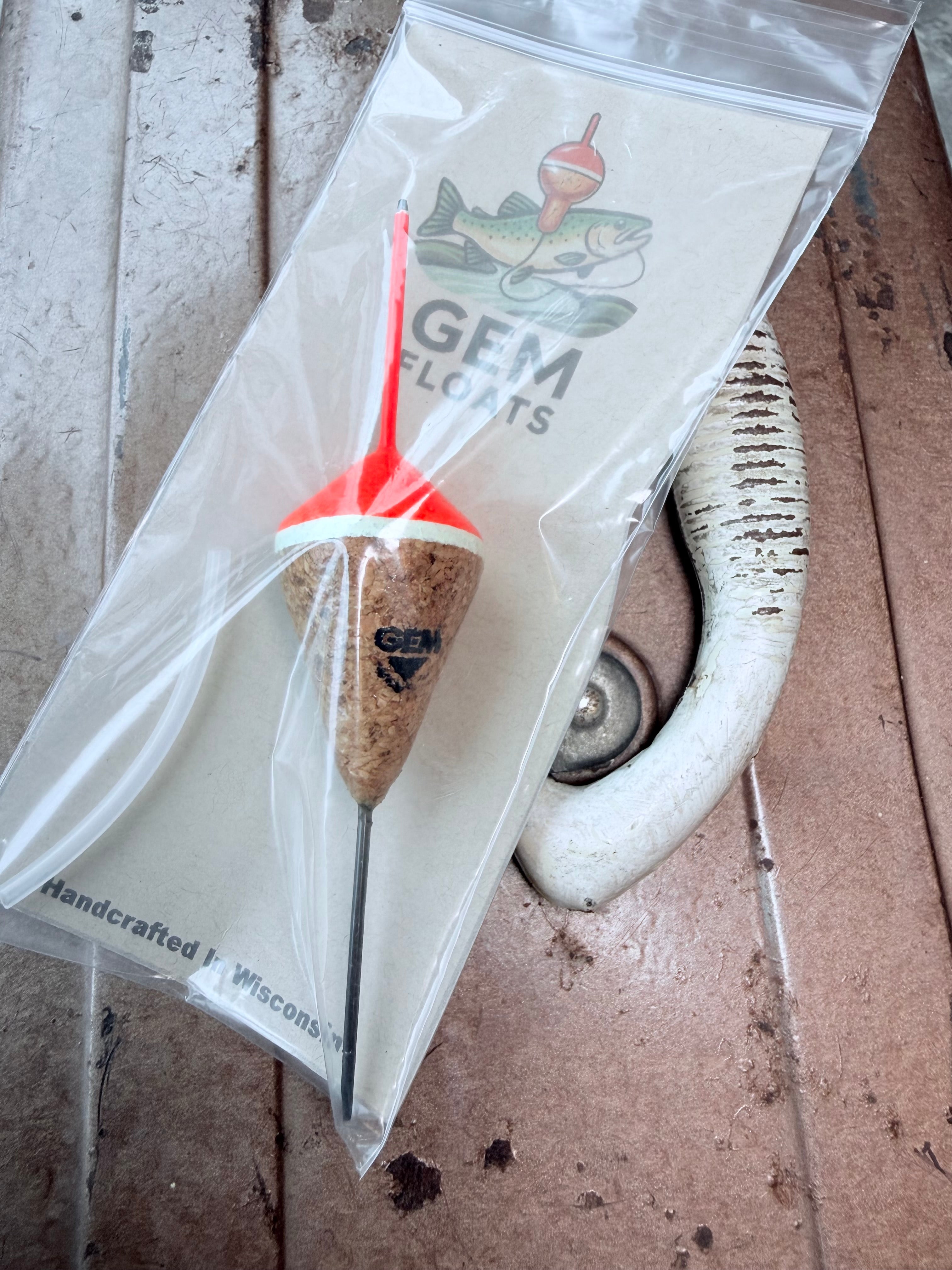 Orange unweighted fixed cork fishing float, inside plastic bag on an antique tackle box. 
