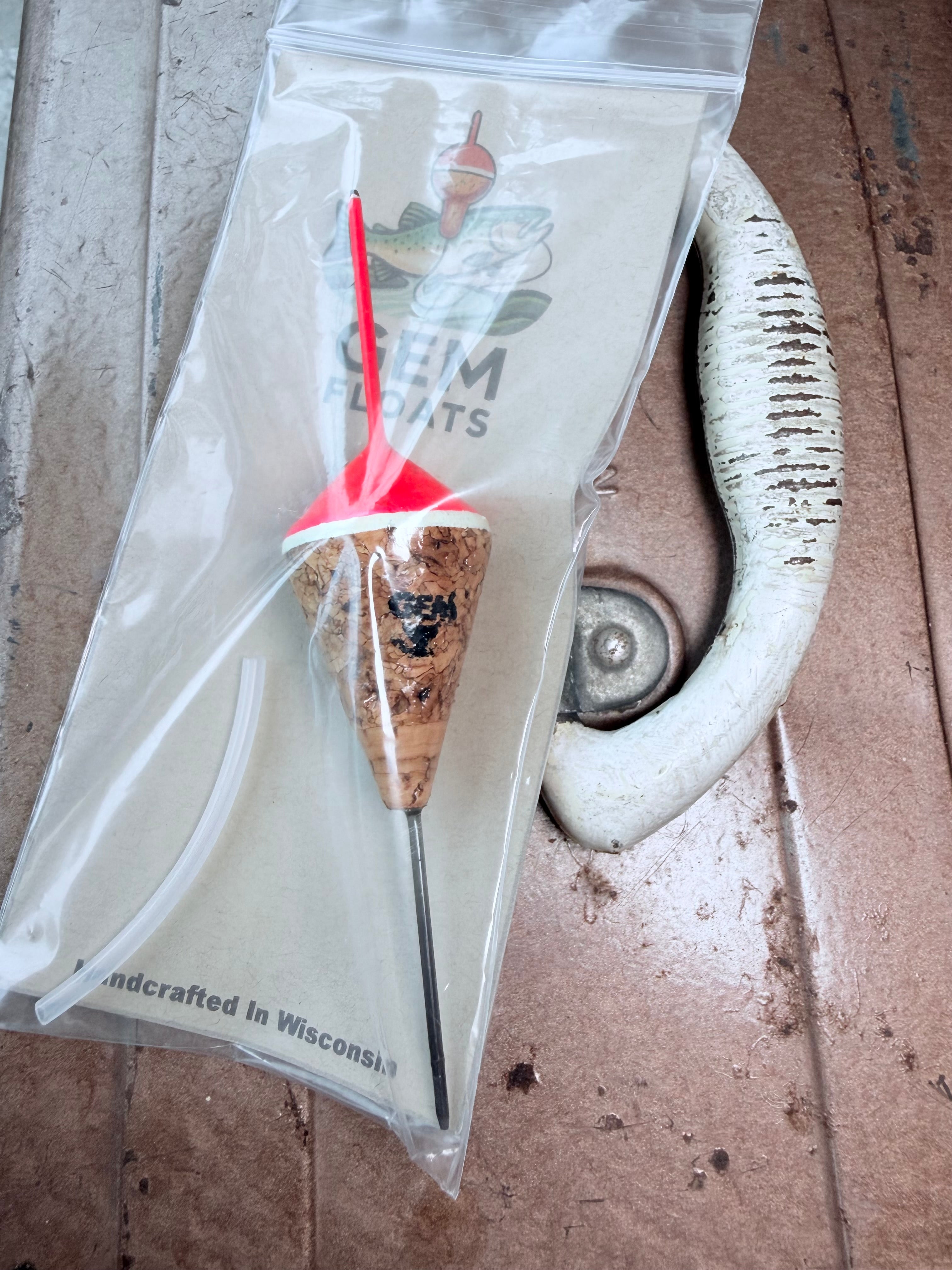 Pink unweighted fixed cork fishing float, inside plastic bag on an antique tackle box. 