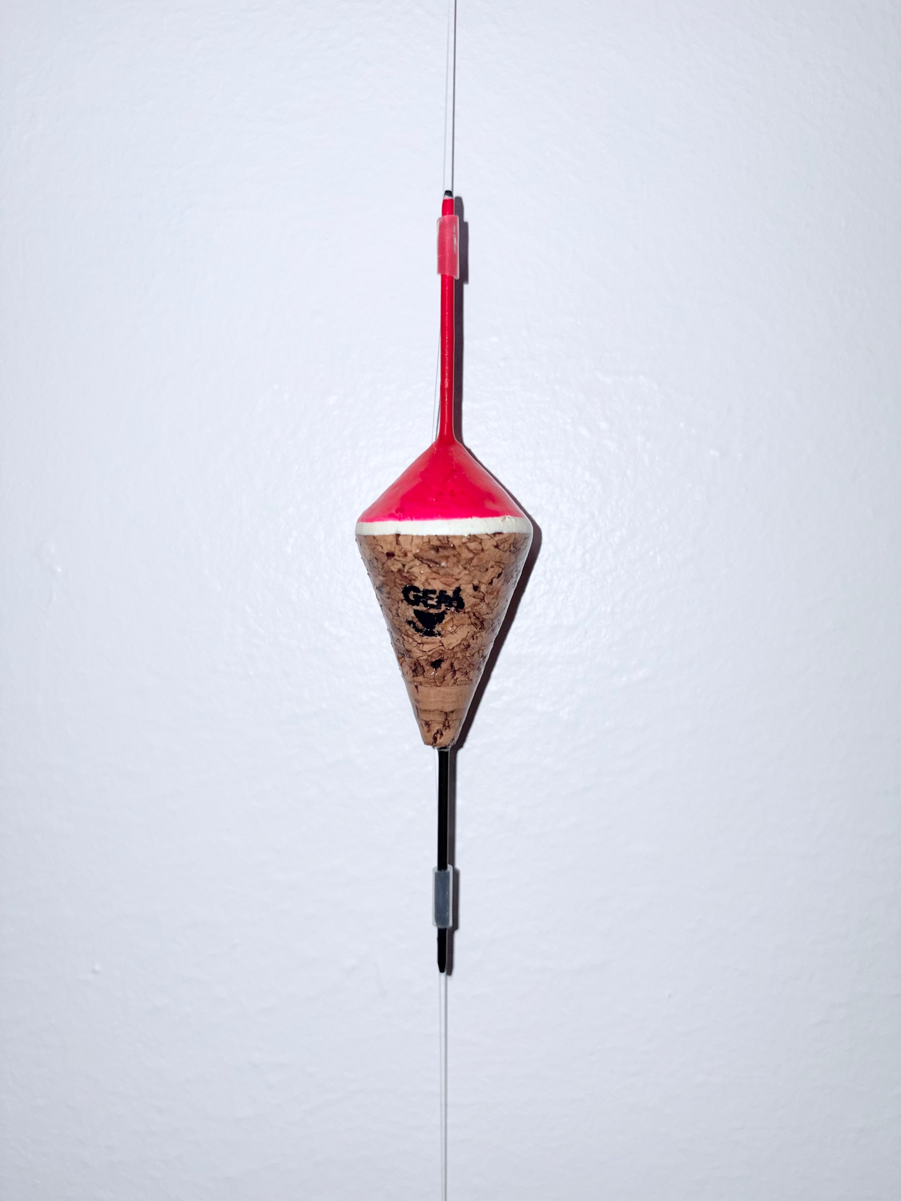 Pink unweighted fixed cork fishing float attached to a fishing line, on a white background.