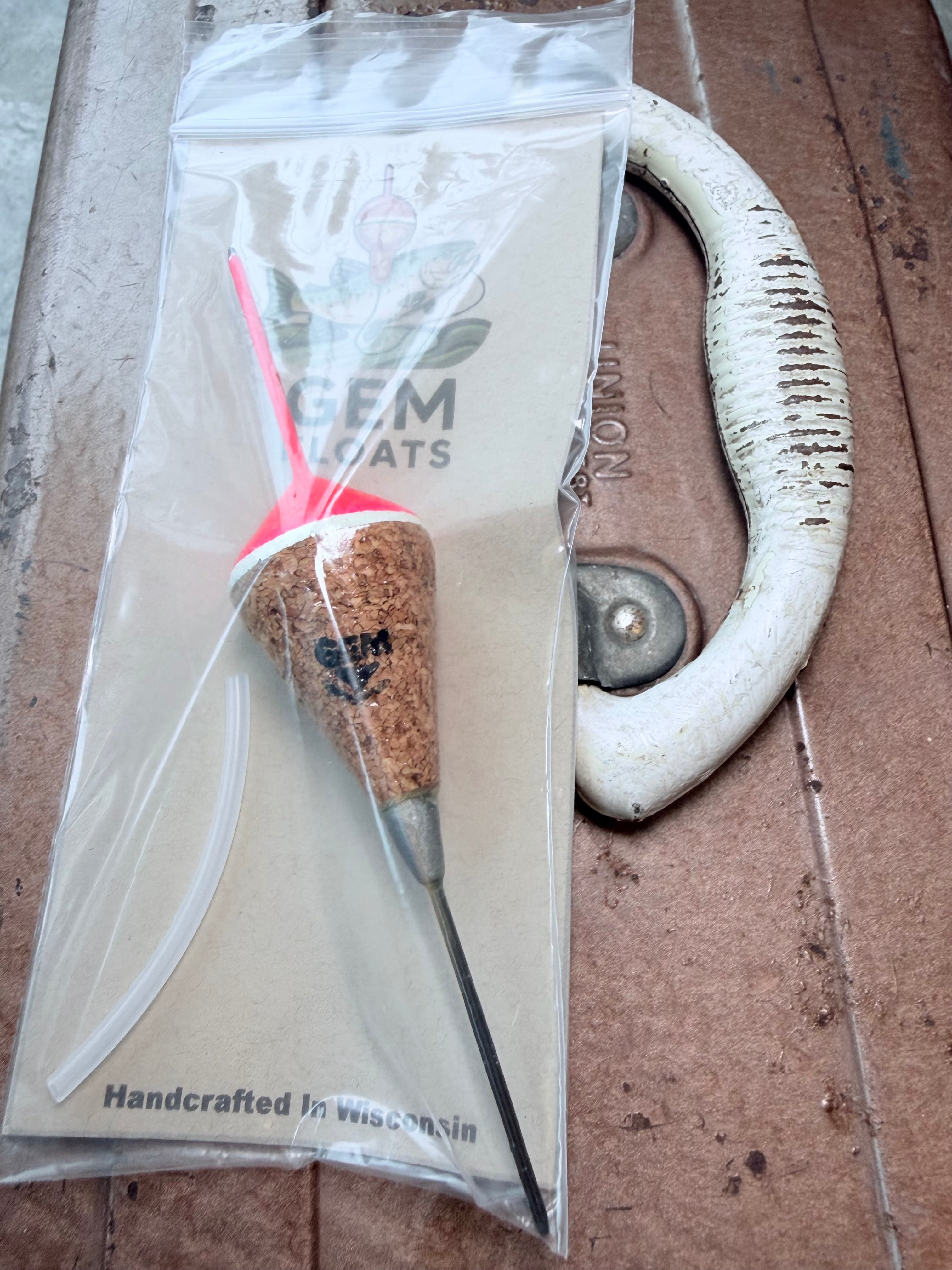 Pink weighted fixed cork fishing float, inside plastic bag on an antique tackle box. 